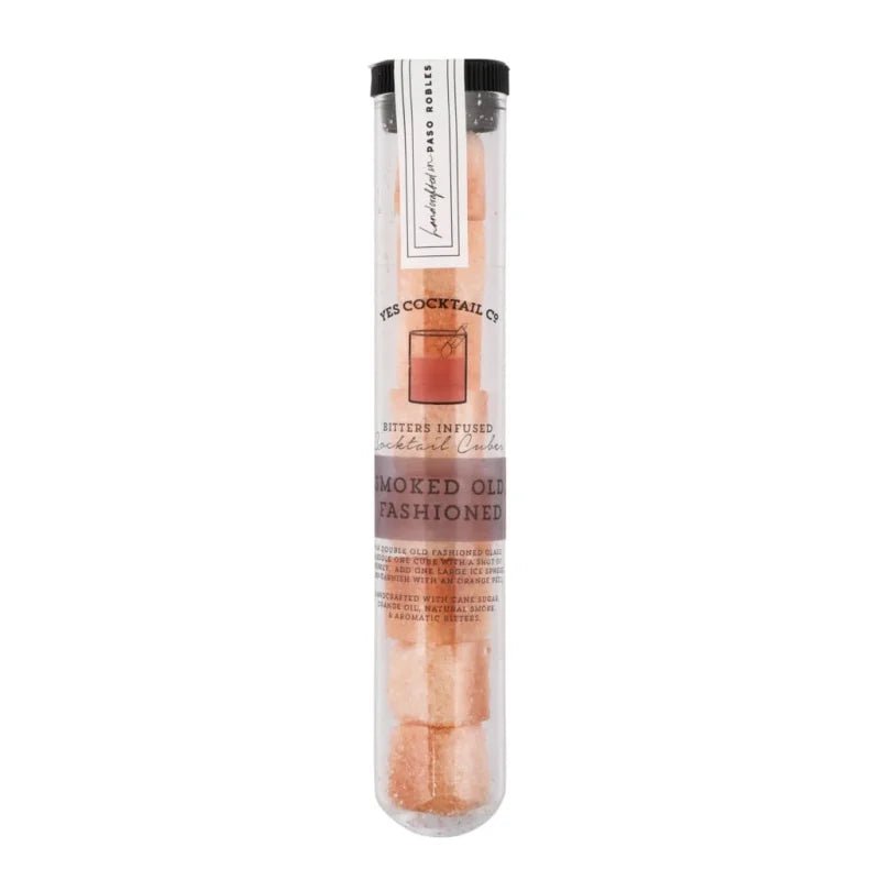 A clear plastic tube contains Yes Cocktail Co.'s Smoked Old Fashioned Cocktail Cubes—pink organic cane sugar cubes, ideal for crafting smoked old fashioned cocktails with bitters.
