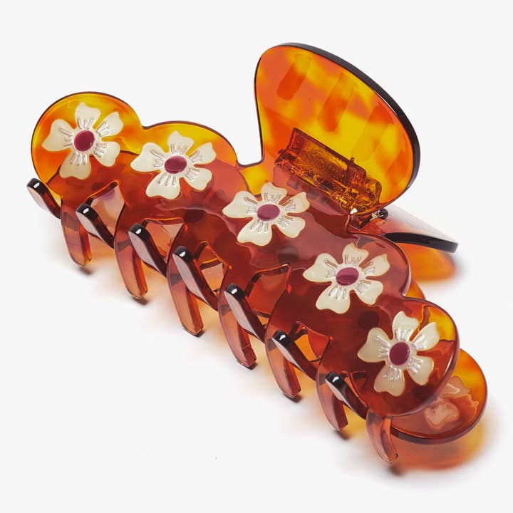 Antheia Claw hair clip in large tortoiseshell acetate featuring a row of white floral cutouts.