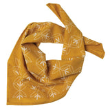 The Cotton Voile Bandana “Against the Odds“ in Saffron by Jenni Earle features white outlined floral and star designs on a yellow cotton voile background, shown laid flat with a knot tied at one side—an ideal lightweight neck scarf that adds vintage bandana charm to your style.
