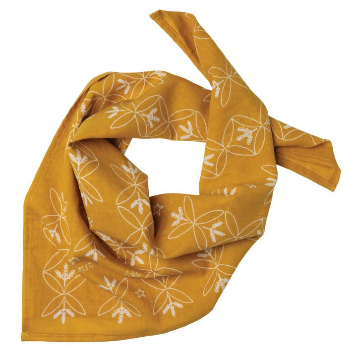 The Cotton Voile Bandana “Against the Odds“ in Saffron by Jenni Earle features white outlined floral and star designs on a yellow cotton voile background, shown laid flat with a knot tied at one side—an ideal lightweight neck scarf that adds vintage bandana charm to your style.
