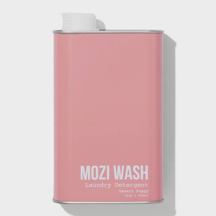 A rectangular pink metal container labeled “Desert Poppy Laundry Detergent | Mozi” with a white screw cap, featuring a delightful floral fragrance reminiscent of fresh laundry and blooming Desert Poppy.