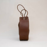 Side view of the Stash Joi Bag in Chestnut Distressed leather, featuring a visible seam, snap button closure, and an adjustable shoulder strap against a plain background.