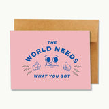 The World Needs What You Got Card by Ramble & Company features a cheerful smiling face giving a thumbs up with the uplifting message “The world needs what you got” in bold blue letters. This blank greeting card is perfect for any occasion.
