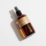 A brown glass spray bottle labeled "N0.32 Sandalwood Rose Room & Linen Spray" by P.F Candle, featuring a black nozzle and pictured on a white background, offers a soothing floral scent of cashmere rose.