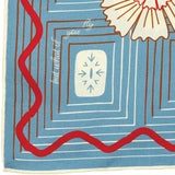 The Jenni Earle Silk Scarf – ‘But What If You Fly’ is a square neck or hair scarf featuring a charming patterned blue silk fabric decorated with white and red shapes, red wavy lines, and the inspiring phrase “but what if you fly” in white script, adding a giftable accessory with a hint of western flair.