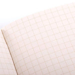 An open 1943 Two-way Memo Book by Field Notes displays a blank page with a light brown grid pattern, evoking the style of classic 1943 Memo Books.