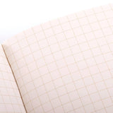 The Field Notes 1943 Two-way Memo Book is open, showing blank graph paper with a grid of evenly spaced squares.