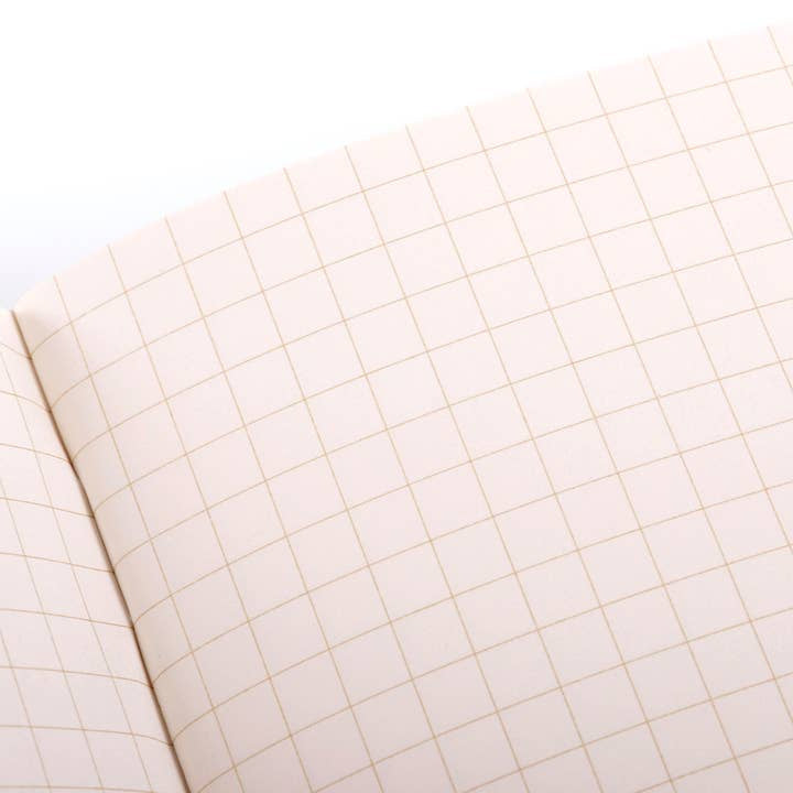 The Field Notes 1943 Two-way Memo Book is open, showing blank graph paper with a grid of evenly spaced squares.