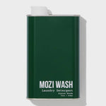 A dark green metal container labeled “Alpine Woods Laundry Detergent | Mozi” in 32oz (946ml) size, featuring a white cap on the top left, evokes fresh pine notes and subtle hints of sandalwood.
