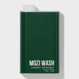 A dark green metal container labeled “Alpine Woods Laundry Detergent | Mozi” in 32oz (946ml) size, featuring a white cap on the top left, evokes fresh pine notes and subtle hints of sandalwood.