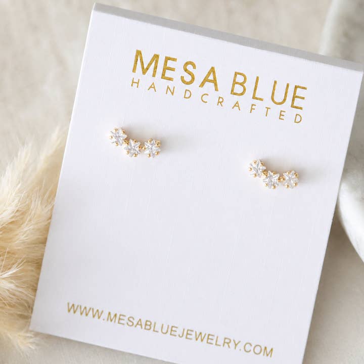 A pair of small Cz Star Climber Stud Earrings by Mesa Blue, featuring 18K gold plating and crystals, displayed on a white Mesa Blue Handcrafted jewelry card.