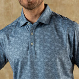 A man wearing the Duck Head Long Drive Performance Polo with a collar and three buttons stands against a neutral beige background.