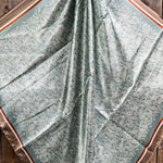 The Rodeo Drive Seafoam and Cream Paisley Wild Rag features intricate white floral motifs with brown and cream borders, perfect for adding western flair to any outfit.