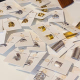 Silver Gladiator Rings by Ornamental Things, featuring intricate metalwork, displayed on white branded cards and arranged neatly on a flat surface.