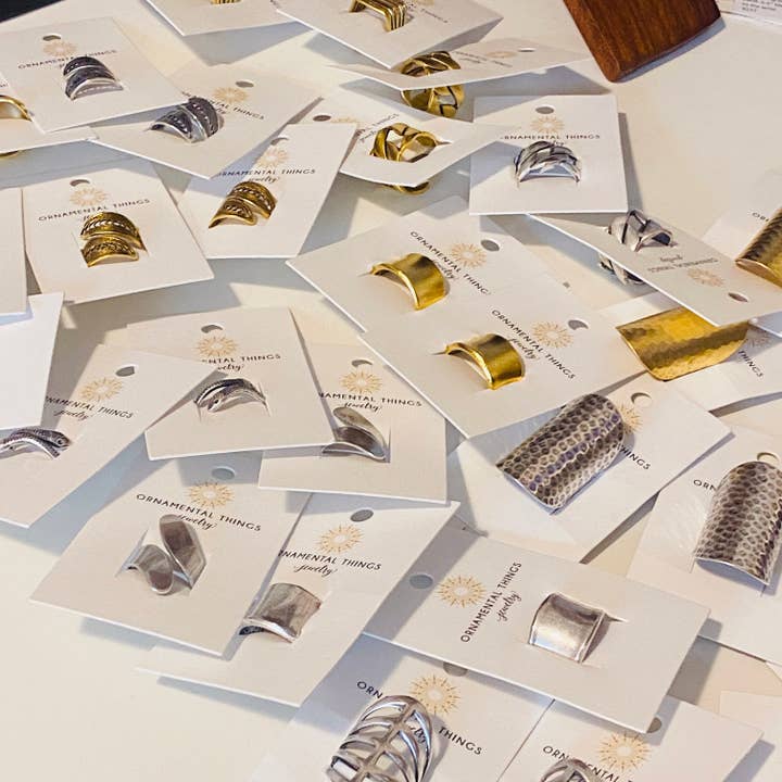 Silver Gladiator Rings by Ornamental Things, featuring intricate metalwork, displayed on white branded cards and arranged neatly on a flat surface.