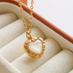 Josie Vintage Heart Pendant Necklace by Flanerie by MAIQ, a gold stainless steel chain with a vintage heart pendant featuring an iridescent white center in an ornate frame.