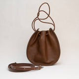 The Joi Bag in Chestnut Distressed by Stash stands upright on a plain white background, featuring an adjustable shoulder strap positioned in front and highlighting its subtle Japanese-inspired handbag design.