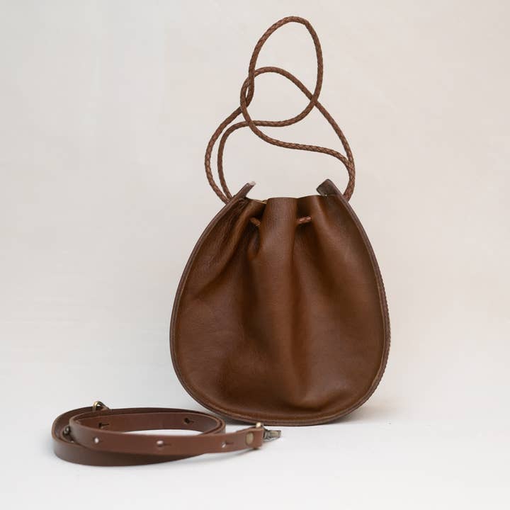 The Joi Bag in Chestnut Distressed by Stash stands upright on a plain white background, featuring an adjustable shoulder strap positioned in front and highlighting its subtle Japanese-inspired handbag design.