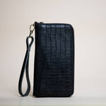 Stash Passport Wallet | Luxe Black Croc stands upright against a plain background, showcasing its sleek crocodile pattern leather finish, secure zip closure, and detachable wrist strap—perfect as a stylish travel accessory.