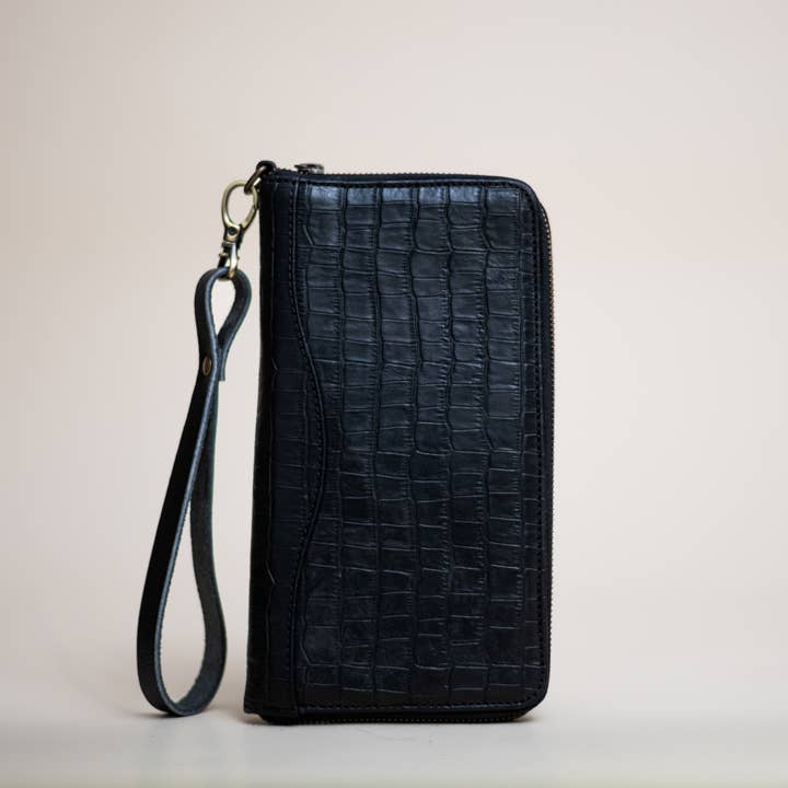 Stash Passport Wallet | Luxe Black Croc stands upright against a plain background, showcasing its sleek crocodile pattern leather finish, secure zip closure, and detachable wrist strap—perfect as a stylish travel accessory.