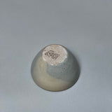 The Stoneware Smudge Bowl by Incausa is a small, hand-thrown ceramic piece with a glossy gray gradient glaze and stamped base, shown upside-down on a plain, light gray surface.