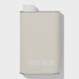 A beige rectangular metal container labeled “Signature Cozy | Mozi” by Mozi, featuring a white cap on top and casting a shadow to the right. This laundry detergent provides a subtle honey fragrance for a refreshing laundry experience.