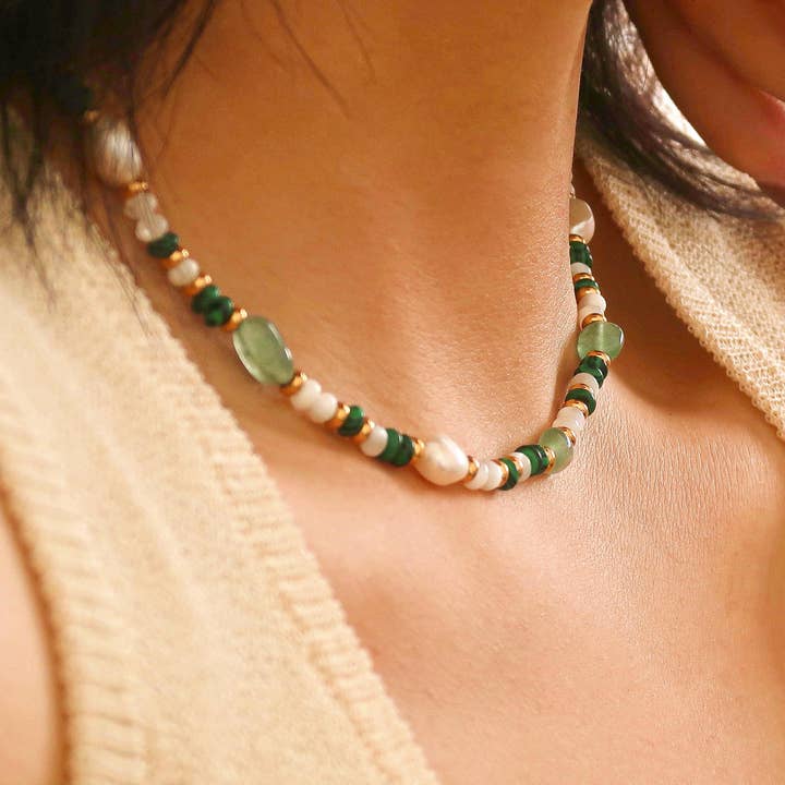 A Bohemian Rose Pearl and Bead Necklace by Flanerie by MAIQ featuring natural pearls, green stone beads, and 18K non-tarnish gold accents worn around a neck.