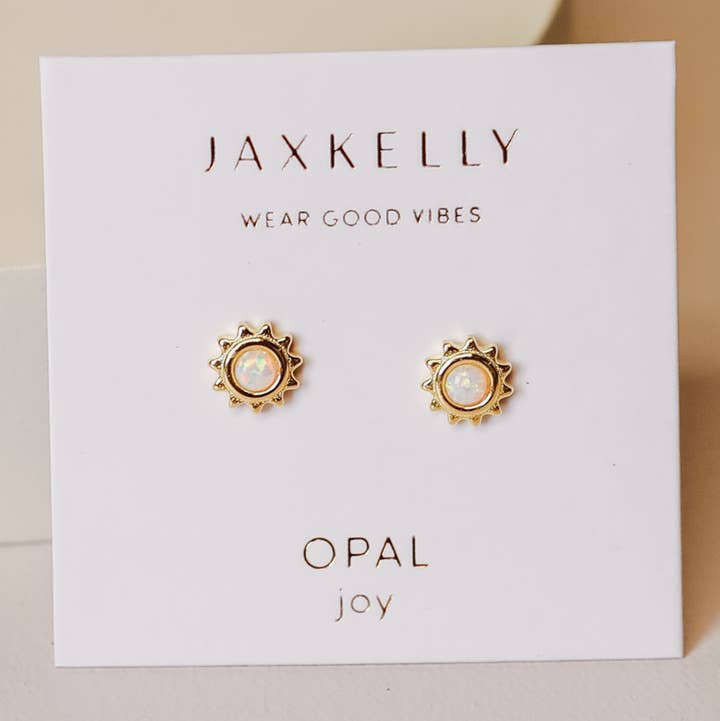 The JaxKelly Sun Stud Earrings by JaxKelly are 18K gold plated, sun-shaped opal studs presented on a white card featuring the phrases “Wear Good Vibes,” “Opal,” and “joy.” These radiant, hypoallergenic earrings add positivity and charm to any jewelry collection.