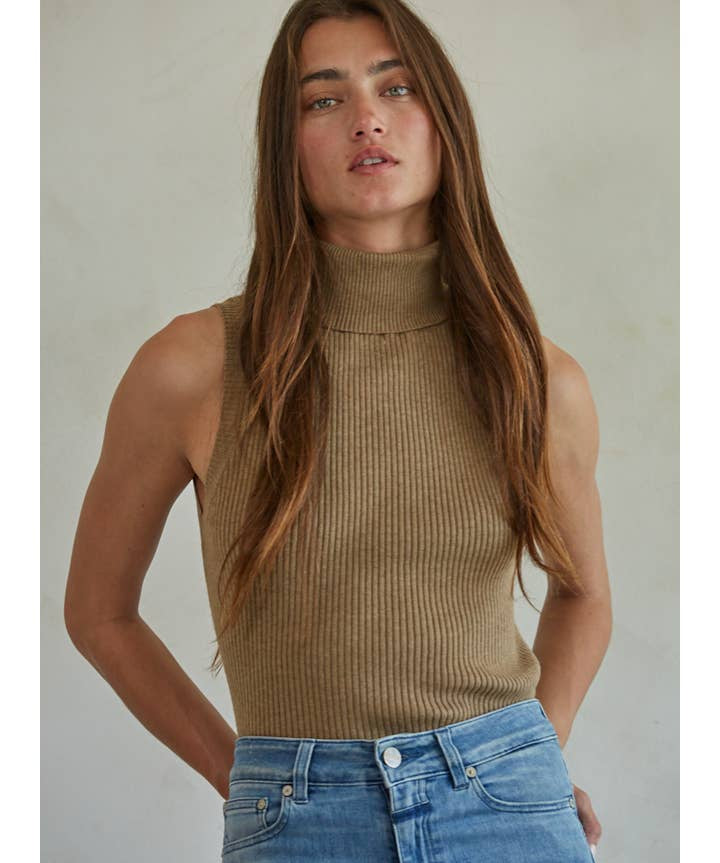 A person wearing a tan Knit Turtleneck Sleeveless Pullover Top in a sleeveless, ribbed turtleneck style.