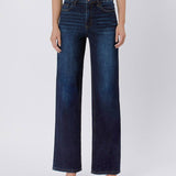 A person models Vervet's 90's Vintage Super High Rise Dark Wash Loose Jeans with a brown top and matching sandals, standing against a plain light background.