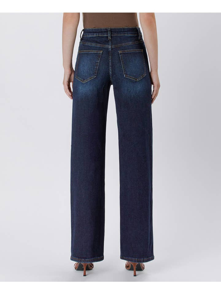 Person wearing Vervet 90's Vintage Super High Rise Dark Wash Loose Jeans and heeled sandals, shown from the back against a plain light background.