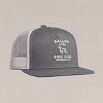 Introducing the Bird Dog Classic Shop Hat by Ballad Originals—a gray and white mesh trucker hat from our Classic Chop Logo Hat collection, featuring our signature shop logo with “Ballad of the Bird Dog, Brenham, TX” and a dog graphic printed on the front panel. A true quality goods accessory.