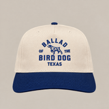 The Field Companion Hat - Ballad Originals by Ballad of the Bird Dog features classic Western styling with a cream and blue design, and showcases “Ballad of the Bird Dog Texas” and a dog graphic embroidered in blue on the front for a timeless look.