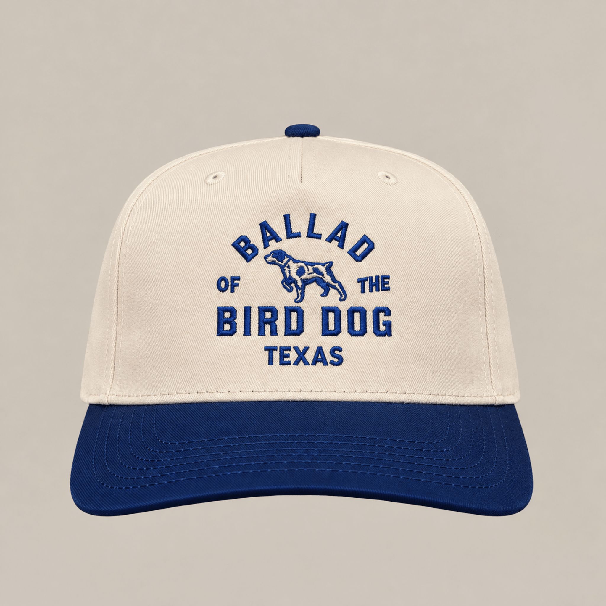 The Field Companion Hat - Ballad Originals by Ballad of the Bird Dog features classic Western styling with a cream and blue design, and showcases “Ballad of the Bird Dog Texas” and a dog graphic embroidered in blue on the front for a timeless look.