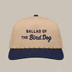 The Ballad of the Bird Dog Desert Series Hat - Ballad Originals features a tan and navy design with perforated sides for enhanced breathability, and “BALLAD OF THE BIRD DOG” embroidered in navy on the front. This athletic hat offers a sweat-resistant construction, making it ideal for all-day comfort.