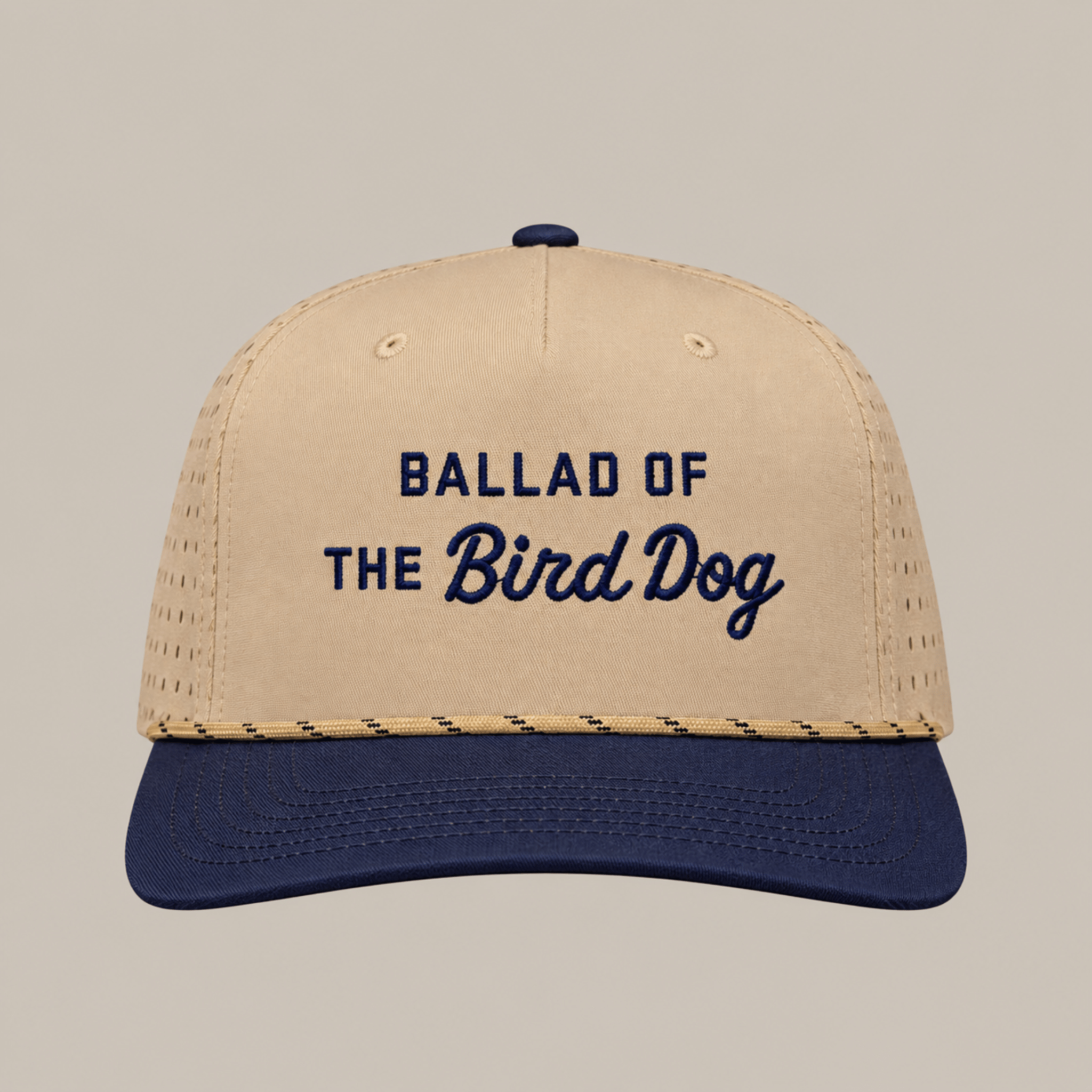 The Ballad of the Bird Dog Desert Series Hat - Ballad Originals features a tan and navy design with perforated sides for enhanced breathability, and “BALLAD OF THE BIRD DOG” embroidered in navy on the front. This athletic hat offers a sweat-resistant construction, making it ideal for all-day comfort.