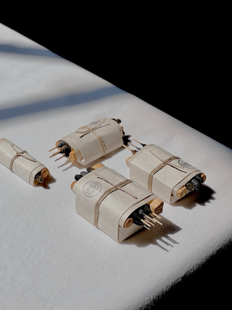 Four Bath & Meditate Bundles by Incausa, each wrapped in white Nepalese Lokta paper and tied with string, are arranged on a white surface in natural light.