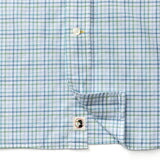 The Cotton Oxford Sport Shirt by Duck Head features light blue, white, and green plaid, a button placket, and a small bird logo patch near the hem, inspired by classic Duck Head OCBD style.