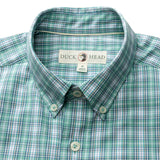 The Duck Head Performance Poplin Sport Shirt is a green and white plaid button-down with collar, collar point buttons, a "Duck Head" label, and moisture-wicking fabric for all-day comfort.
