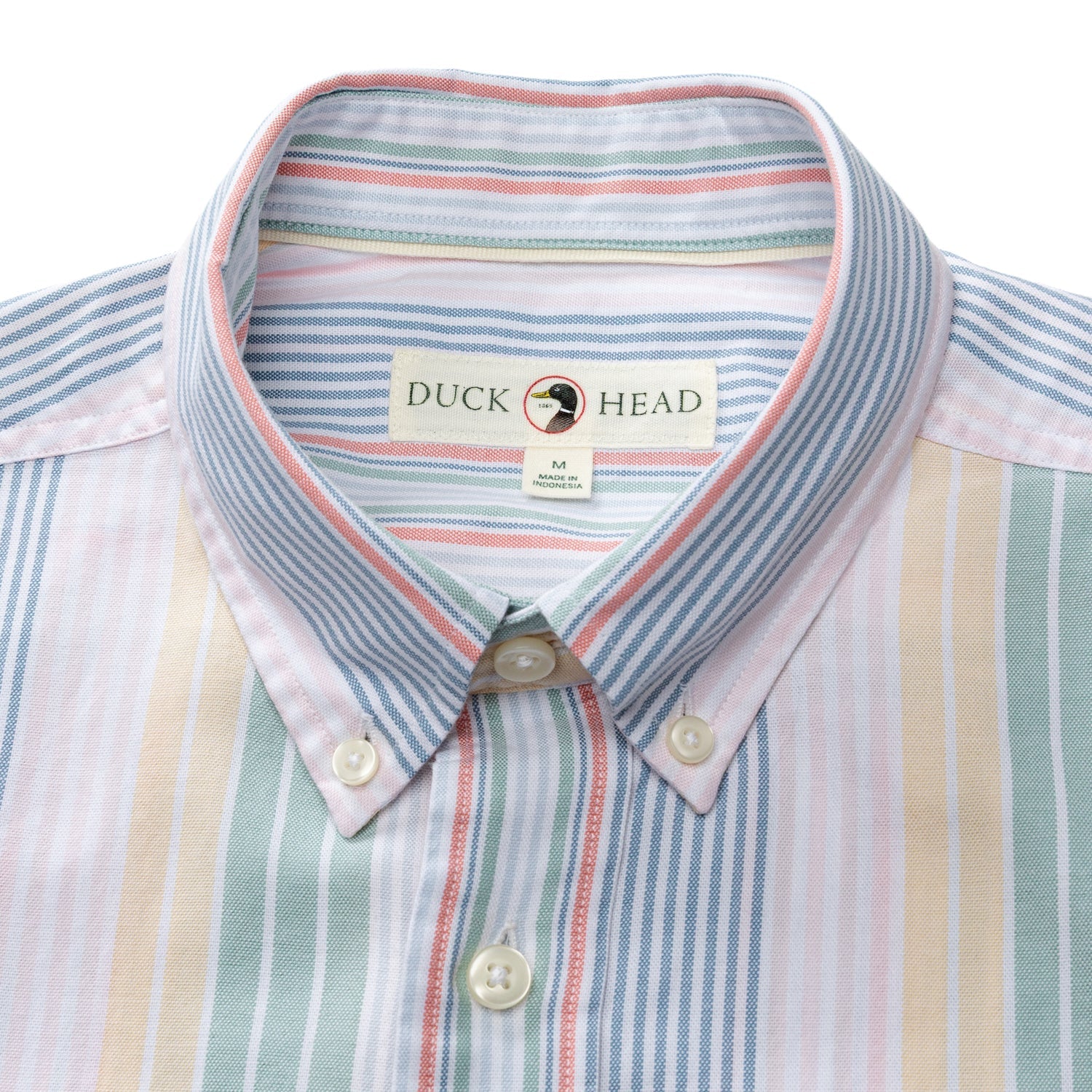 A close-up of the Duck Head Cotton Oxford Sport Shirt, featuring vertical pastel stripes in blue, pink, yellow, and green with mechanical stretch and a "Duck Head" label on the collar.