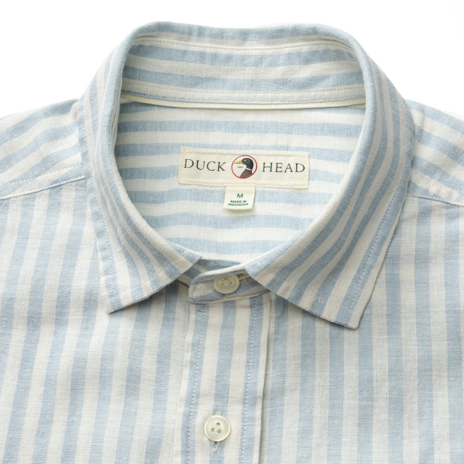The Duck Head Linen Cotton Oxford Sport Shirt, in light blue and white stripes with a button-down collar and medium size tag, blends comfort and classic style in a garment washed finish.