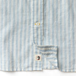 Close-up of the Duck Head Linen Cotton Oxford Sport Shirt, featuring blue and white vertical stripes, a button-down collar, and a small bird logo patch near the hem.