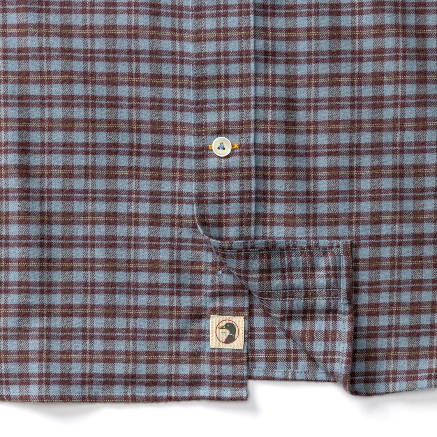 Duck Head Cotton Flannel Sport Shirt in blue and brown cotton flannel, featuring a button placket and a circular logo patch near the hem.