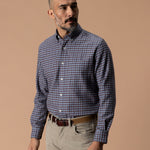 A man wearing a blue and brown Cotton Flannel Sport Shirt Duck Head tucked into tan trousers with a leather belt.