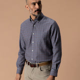 A man wearing a blue and brown Cotton Flannel Sport Shirt Duck Head tucked into tan trousers with a leather belt.