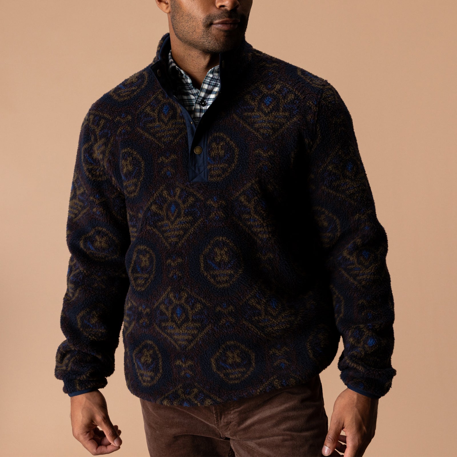 A man wearing a patterned Pineview Fleece 1/4 Snap Pullover over a plaid shirt for lightweight warmth during outdoor activities.