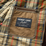 Interior view of a Duck Head Fremont Lodge Performance Quilted Jacket with a plaid lining and a zippered pocket featuring a label that reads “Fremont Lodge Jacket, made to be worn since 1865.”.