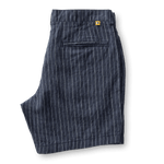 Duck Head Gold School Linen Chino Shorts in navy blue pinstripe feature a back pocket, antique brass button, YKK metal zipper, and a yellow tag above the pocket, shown on a white background.