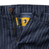 Close-up of Duck Head Gold School Linen Chino Shorts in blue pinstripe, featuring a YKK metal zipper, antique brass button, and partially open to show yellow inner label and detailed stitching.