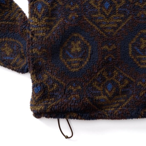 Close-up of a Pineview Fleece 1/4 Snap Pullover by Duck Head, featuring a dark blue and brown geometric pattern and a drawstring hem for lightweight warmth.